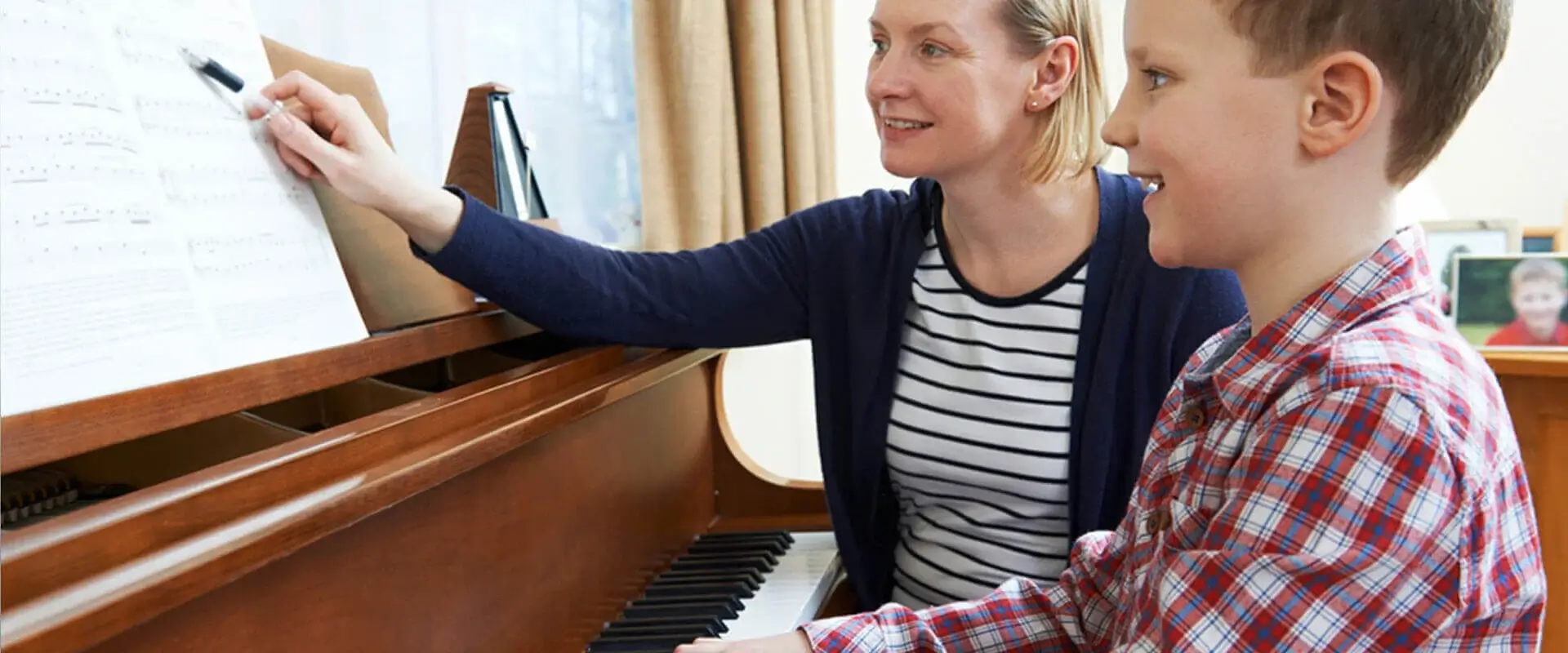 piano teacher and student sitting at a piano