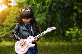 child with a smile holding a guitar